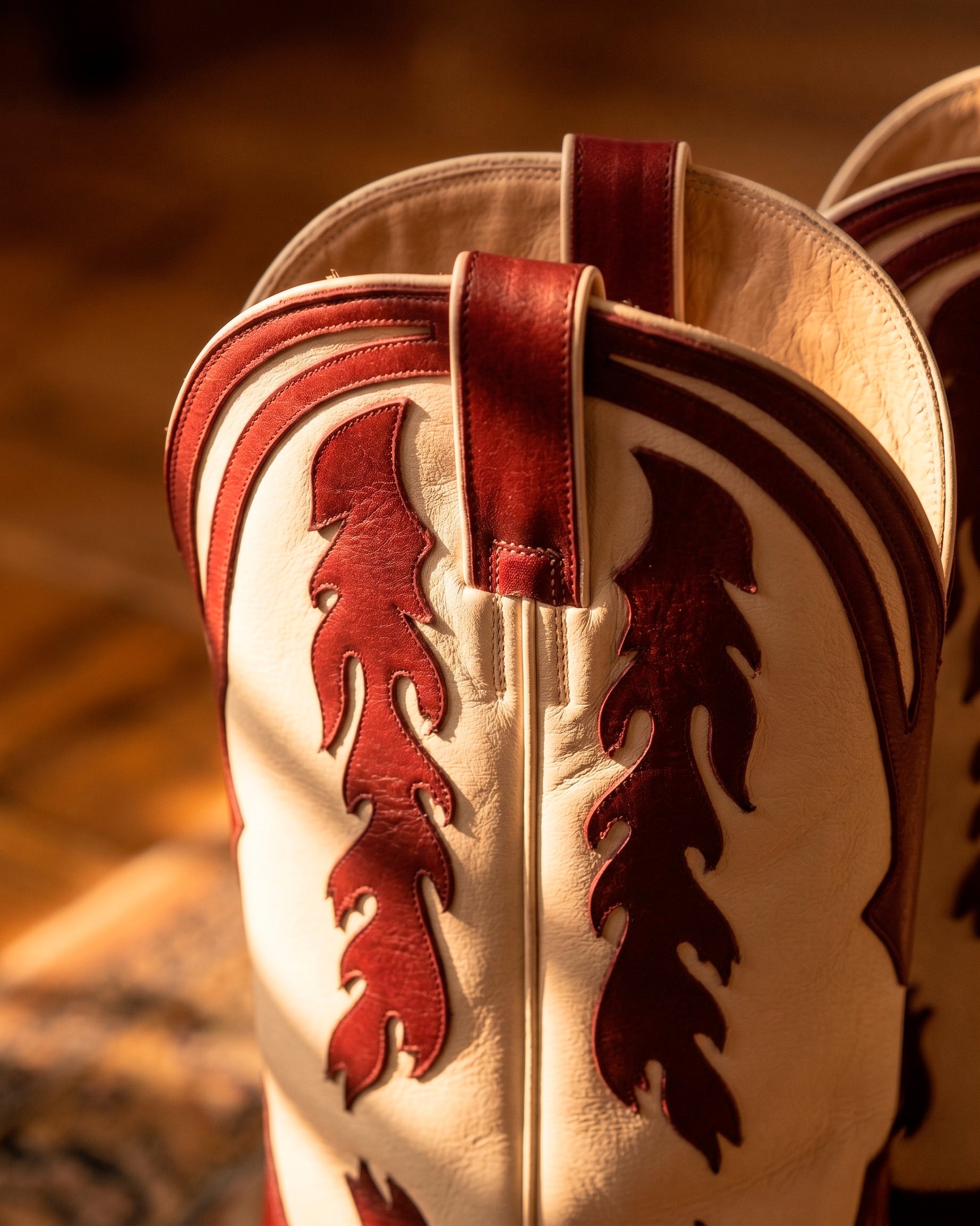 Detailed close-up of red leather inlay stitched into a cream cowboy boot shaft.